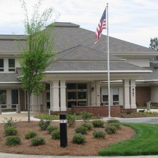A building with an American flag on a flagpole, surrounded by landscaped grounds.