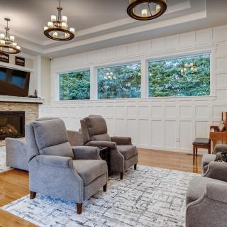 A cozy living room featuring modern recliner chairs, a fireplace, and large windows that provide natural light.