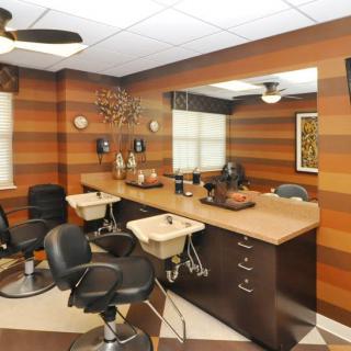 A stylish hair salon interior with comfortable chairs, large mirrors, and wood-paneled walls.