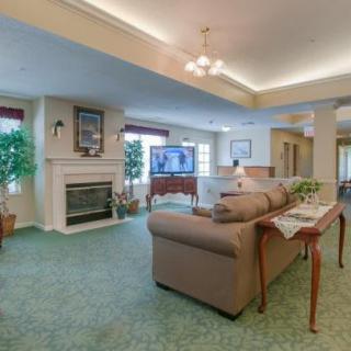 A spacious living room featuring a fireplace, comfortable seating, a large television, and decorative plants.