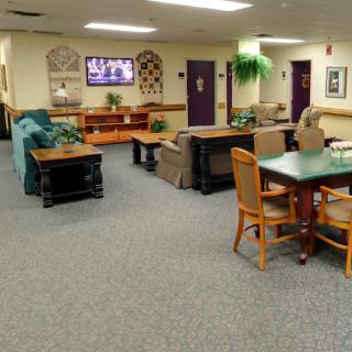 A comfortable lounge area featuring sofas, chairs, tables, and a television on the wall.