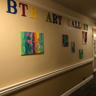 A hallway transformed into an art gallery, featuring a colorful display of paintings on the wall.