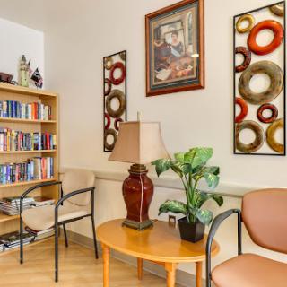 A cozy corner of a living room featuring a bookshelf, decorative artwork, and comfortable seating.