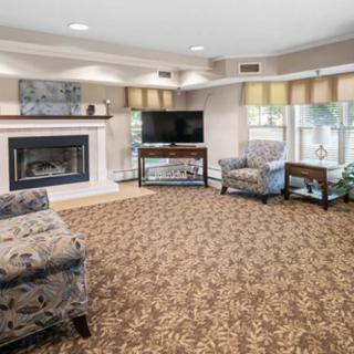 Cozy living room with fireplace and television, featuring comfortable seating and large windows.