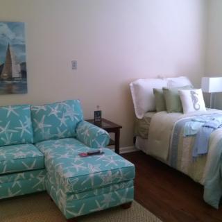 A cozy living area with a patterned sofa and a neatly made bed, showcasing pastel interior design.