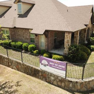 A well-maintained residential home with a decorative fence and lush landscaping.