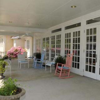 A cozy patio with colorful rocking chairs and plants.