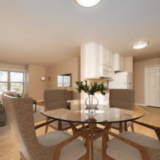 A modern open-concept dining and living area featuring a round table and ample natural light.