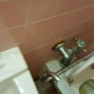 A bathroom with a toilet and sink featuring pink tiled walls.