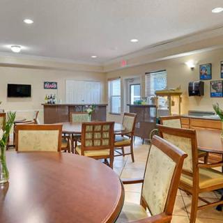 An indoor dining area with neatly arranged tables and chairs, decorated with simple decor and illuminated by ceiling lights.