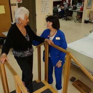 A healthcare professional assists an elderly patient with physical therapy exercises.