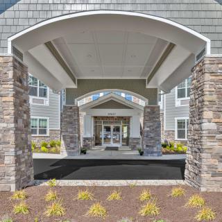 The entrance of a modern building with stone columns and a covered walkway.