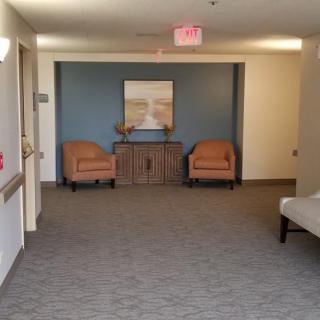 A quiet, well-furnished lobby with two chairs, a cabinet, and decorative artwork on the wall.