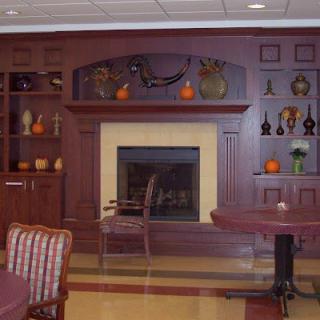 A cozy indoor seating area with a decorated fireplace surrounded by shelves featuring vases and pumpkins.
