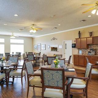 A spacious dining room with elegant seating and a kitchen area in the background.