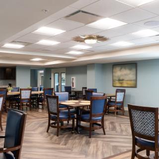 A neatly arranged dining area with multiple tables and chairs, well-lit with overhead lights.