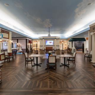 A spacious dining area with elegant decor, featuring wooden floors, tables, and chandeliers.