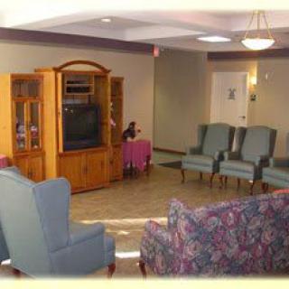 A cozy living room with comfortable chairs, a sofa, and a television cabinet.