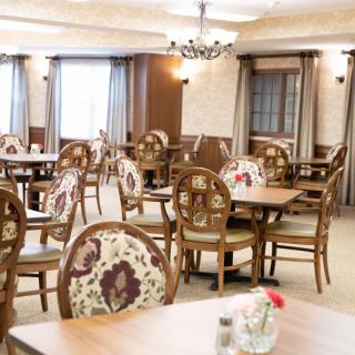 An elegantly decorated indoor dining area with wooden tables and floral-patterned chairs.