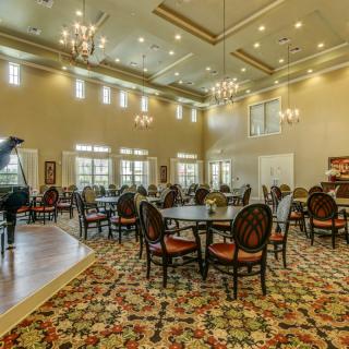 Spacious and elegant dining area with chandeliers and round tables.