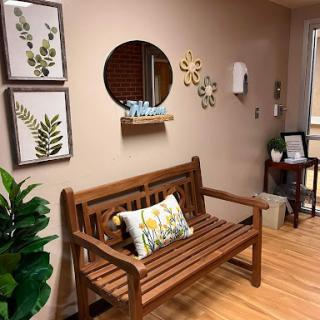 A cozy corner featuring a wooden bench, decorative wall art, and plants, creating a welcoming atmosphere.