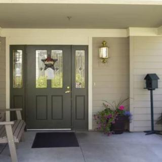 A welcoming front porch with a green door, outdoor seating, potted plants, and a mailbox.