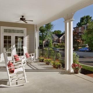 A charming porch with rocking chairs and potted plants overlooking a suburban neighborhood.