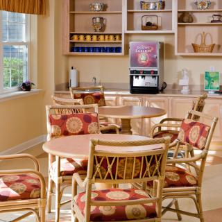 A cozy dining area with tables, chairs, and a beverage machine.