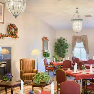 A cozy dining room setup with tables and chairs arranged neatly, adorned with elegant chandeliers and vibrant plants, creating a warm and inviting atmosphere.