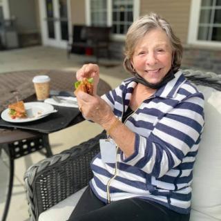 A woman enjoying a meal with coffee while seated outdoors.