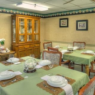 A well-arranged dining room featuring green table settings and a wooden cabinet.