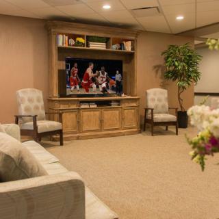 A cozy living room with a television, comfortable seating, and decorative plants.