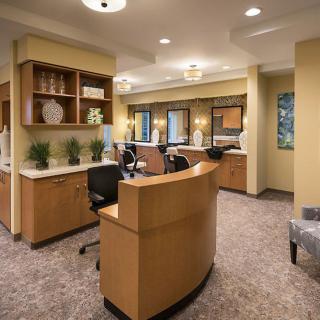 A modern office reception area featuring a curved desk, comfortable seating, and decorative plants.