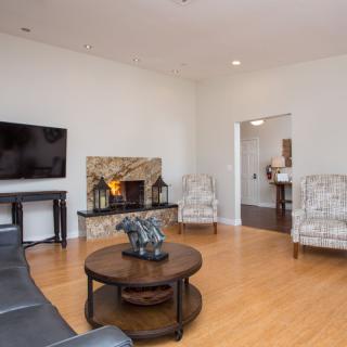 A modern living room with a television and fireplace, featuring wood flooring and stylish furnishings.
