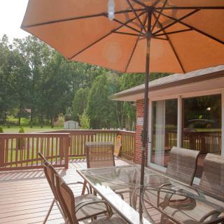 A cozy backyard patio with a table, chairs, and an umbrella providing shade.