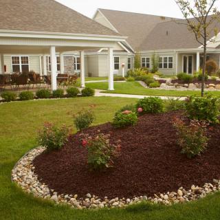 A beautifully landscaped garden with a pathway and mulched shrub area in front of residential houses.