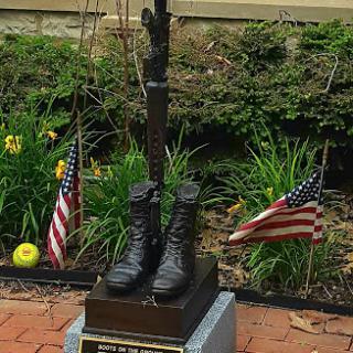 A tribute to military service featuring a statue of boots and a flag, symbolizing honor and remembrance.