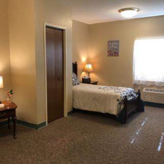 A cozy bedroom with a single bed, two lamps, and a window providing natural light.