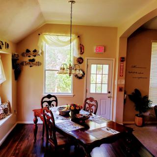 A cozy dining room with a wooden table set for four, featuring elegant chairs and a decorative chandelier.