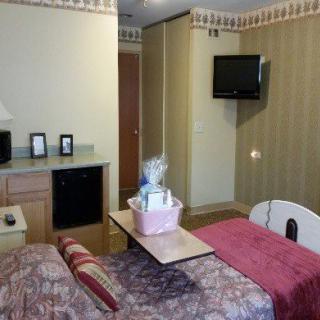 A hospital room featuring a bed with a gift basket, a wall-mounted television, and decorated walls.