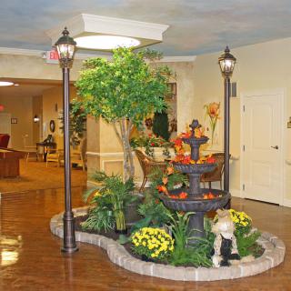A beautifully decorated indoor garden with a fountain and lampposts in a lobby setting.