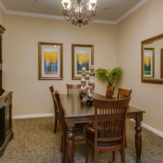 A warmly decorated dining room with a wooden table, chairs, chandelier, and vibrant wall art.