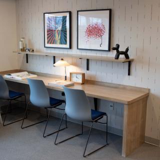 Contemporary workspace with a wooden desk, modern chairs, and decorative artwork.
