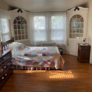 Cozy bedroom with antique furniture and sunlight streaming in through the windows.
