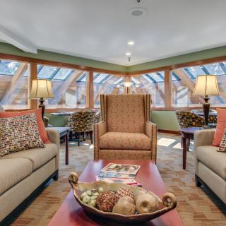 A cozy living room featuring large windows, comfortable sofas, and warm lighting.