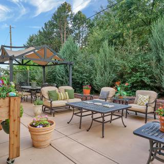 A cozy outdoor patio with cushioned seating and potted plants under a gazebo.