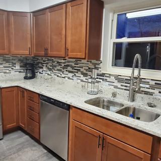 A modern kitchen featuring wooden cabinets, granite countertops, a dual sink, and a stainless steel dishwasher.