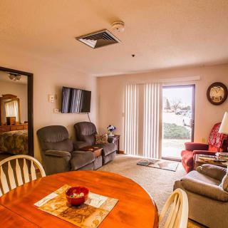 A cozy living room with a dining area, featuring comfortable sofas, a TV, and a wooden dining table.