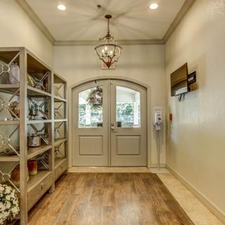 A beautifully decorated entryway featuring a chandelier, shelves with decor, and double doors.
