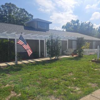 A suburban house with an American flag displayed in the yard on a sunny day.